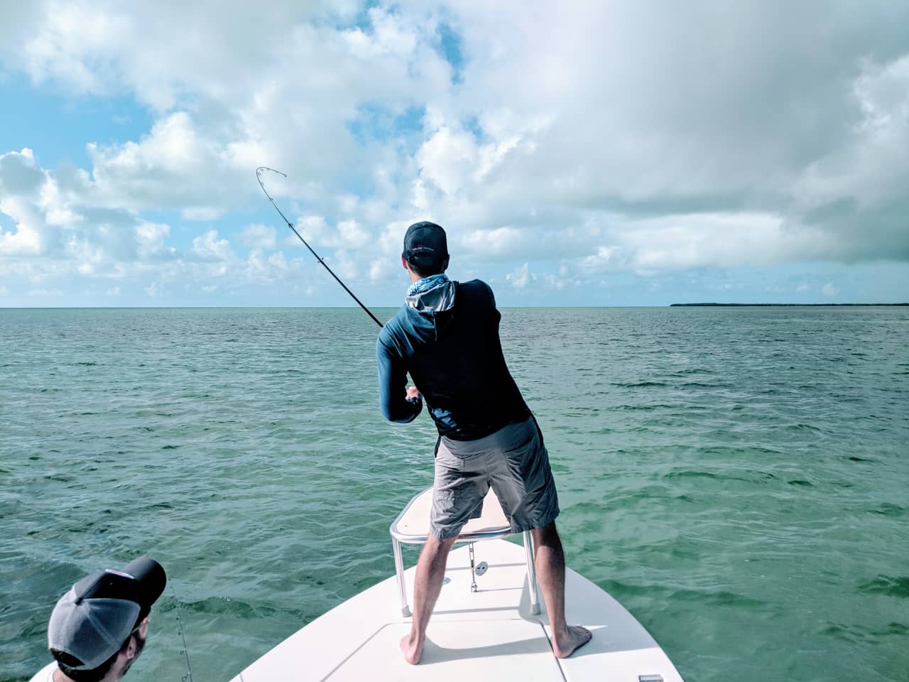An angler on the bow of Capt. Shane Wood's flats skiff fights a fish on a Key West flat