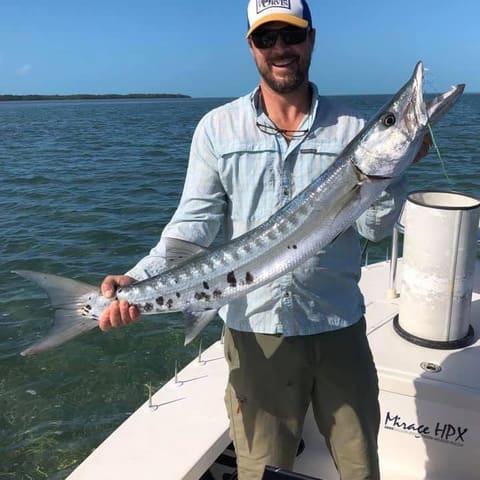 Angler holding a barracuda on the bow of the Maverick HPX skiff