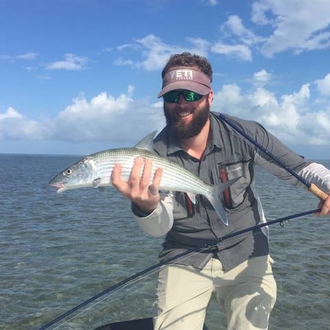Angler with a fly rod holding a bonefish on the flats