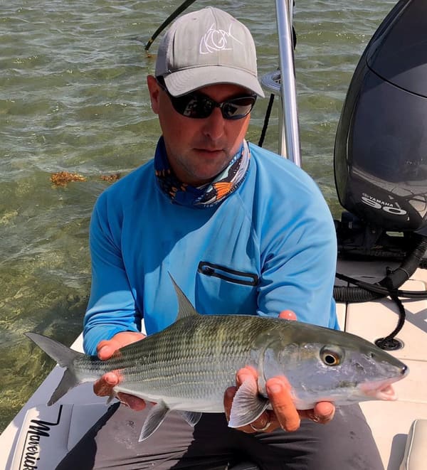 Captain Shane Wood holding a bonefish aboard his Maverick flats skiff