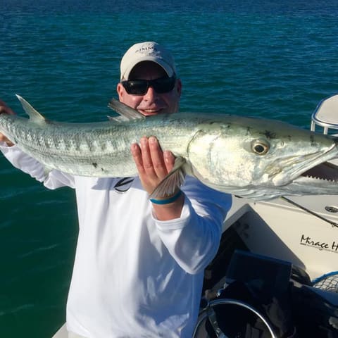 Angler holding a great barracuda aboard the skiff