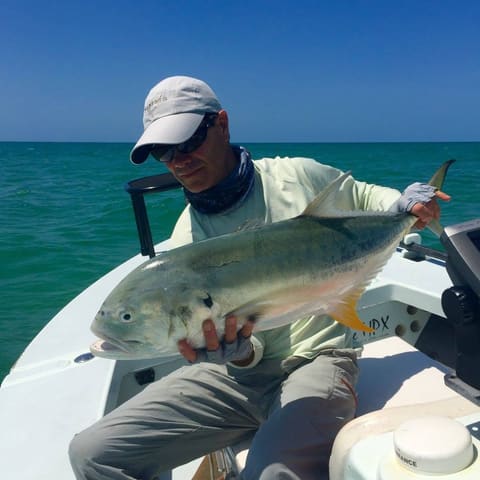 Angler holding a jack crevalle in the skiff