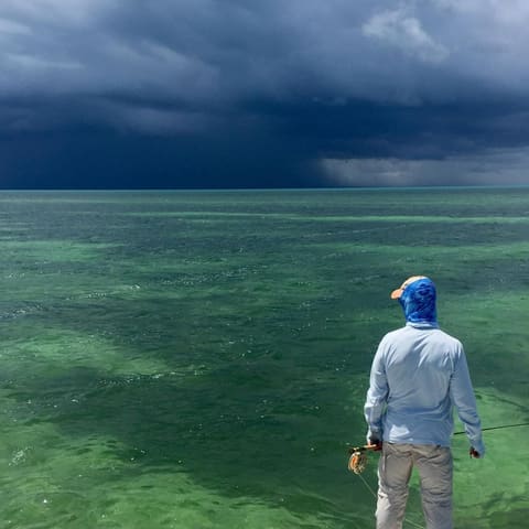 Angler standing on a Key West flat as a storm builds on the horizon