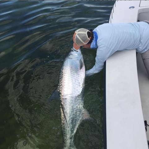 Guide reviving a tarpon alongside the skiff before letting it go